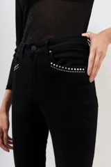 Pantalón jean negro de corte slim con detalles de tachas plateadas en los bolsillos delanteros y en el ruedo.