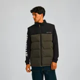 Chaleco acolchado Caterpillar, color marrón con parte superior negra, cierre frontal con cremallera, cuello alto y bolsillos laterales con cierre.