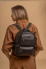 Mochila funcional color beige con detalles en negro, que incluye dos compartimentos con cierre y un bolsillo frontal para fácil acceso.