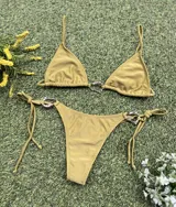Conjunto de bikini color verde pistacho, con corpiño triangular con argolla metálica plateada en el centro y bombacha colaless con tiras para atar y argollas en los costados.
