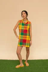 Vestido corto sin mangas con estampado de cuadros en tonos azul, rojo, verde y blanco. Tiene cuello redondo y ruedo con flecos.