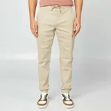 Pantalón cargo color beige, de corte slim fit, con cintura ajustable con cordón, bolsillos laterales con solapa y puños elásticos.
