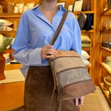 Bandolera marrón con paneles combinados en tonos beige y verde. Tiene apertura superior con cierre, bolsillo frontal con cierre, tres bolsillos internos (dos con cierre), bolsillo trasero con cierre y correa larga regulable.