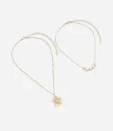 Set de dos collares dorados con dije de flor y perlas.