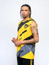 Musculosa deportiva sin mangas, color amarillo con diseño gráfico abstracto en negro y gris. Presenta un escudo de equipo de fútbol en el pecho izquierdo.