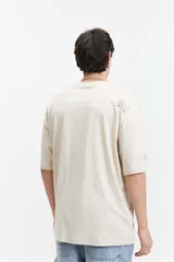 Remera color crema de manga corta con corte boxy, cuello redondo y logo estampado en el pecho.