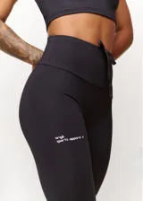 Calza deportiva negra de tiro alto con cordón ajustable en la cintura y logo estampado en la pierna.