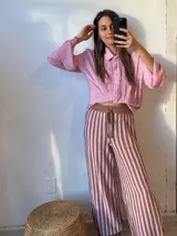 Camisa rosa con cuello clásico, abotonada al frente y mangas largas con puños abullonados.