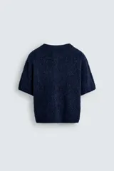 Cárdigan azul marino de manga corta tejido en hilatura con lana y alpaca, de textura suave. Tiene cuello redondo, rib en los bordes y cierre frontal con botones. Edición especial Harry Lambert for Zara x Disney.