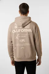 Canguro gris claro melange con capucha ajustable y cordones. Presenta un estampado frontal en color verde oscuro con la frase "Costa Amalfi" y texto adicional. Tiene un bolsillo canguro en la parte delantera y puños y dobladillo acanalados.