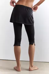 Calza deportiva cropped negra con una mini falda superpuesta de tiro alto y elástico. La calza presenta costuras deportivas y aberturas en los tobillos.