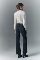 Pantalón de jean negro de tiro medio, corte ajustado en la cintura y muslos, y acampanado desde la rodilla hasta el ruedo. Confeccionado en tejido confort con elastano, cierre y botón.