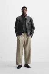 Pantalón negro de corte amplio tipo balloon fit, con cintura con pliegues frontales, bolsillos delanteros y traseros de plastrón. Cierre frontal con cremallera y botón.