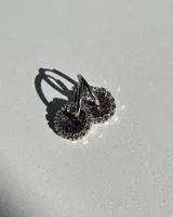 Aritos mini con dije circular de resina con glitter multicolor y strass plateados en el borde. El arito es de acero quirúrgico.