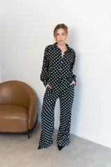Camisa negra con estampado de lunares blancos, de manga larga y cuello clásico.