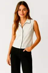 Camisa blanca sin mangas, con cuello clásico, corte al cuerpo y vivos negros en cuello y botones.