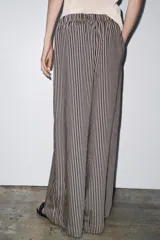 Pantalón de tiro medio con cintura elástica y bolsillos laterales ocultos en costura. Pierna ancha y diseño a rayas verticales azules y blancas.