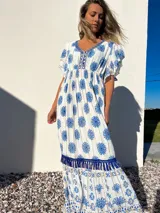 Vestido largo blanco con estampado floral azul, escote en V con bordado y mangas cortas con volados.