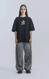 Remera negra de manga corta con cuello redondo y calce oversize. Estampado frontal de Mickey Mouse andando en skate.