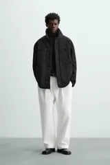 Parka negra de algodón con cuello solapa de cuero sintético, corte recto, acolchada, con bolsillos de parche y cierre frontal con botones.
