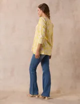 Blusa amarilla con estampado floral blanco, escote en V y mangas 3/4.