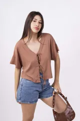 Remera color amarillo pálido de corte holgado, escote en V con lazo y mangas cortas.