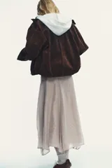 Falda midi color beige de tejido fluido, con tiro medio, cremallera lateral oculta y forro interior combinado.