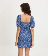 Vestido corto azul con estampado floral blanco, escote cuadrado, mangas cortas abullonadas y textura.