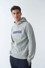 Buzo canguro de felpa color bordó, con capucha ajustable con cordones blancos, fit regular, manga larga, bolsillo canguro y logo estampado en el pecho.