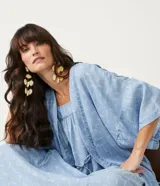 Kimono de lyocell (tejido tipo jean) color celeste claro con estampado repetitivo de pequeños peces blancos. Diseño de manga corta ancha y abertura frontal que se ajusta con un lazo fino en la cintura.