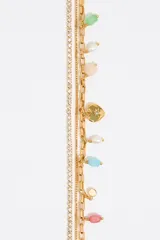 Collar dorado con tres cadenas de diferentes diseños, cristales y dijes de piedras de colores y un dije de corazón dorado.