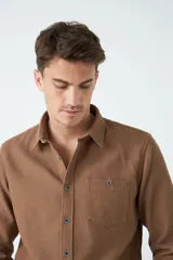 Camisa marrón de manga larga con bolsillo en el pecho y cierre con botones.