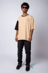 Remera color arena con manga corta negra, cuello redondo con ribete negro y estampado pequeño en el pecho con la frase "Don't worry be happy".