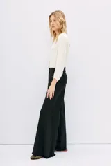Pantalón de jean negro de corte oxford, tiro medio, con cintura y cadera ajustadas, y piernas anchas con recortes laterales.