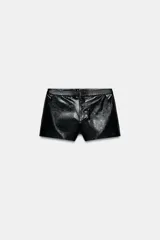 Shorts negros de tiro bajo con acabado brillante que simula cuero, cierre frontal con cremallera y gancho metálico, y bolsillos delanteros.