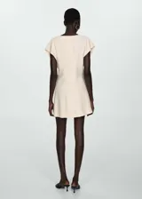 Vestido corto color crema, con cuello en V, mangas cortas y detalle de bordado en el pecho.