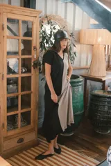 Vestido largo de tejido acanalado, con diseño bicolor vertical: mitad negro y mitad beige claro. Tiene mangas cortas y escote en V.