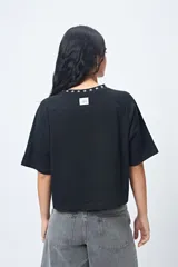 Remera negra de corte holgado con mangas ranglan y cuello redondo con bordado de estrellas blancas.