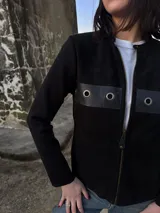 Campera negra de lana con frente de cuero, cierre frontal con cremallera y mangas largas.