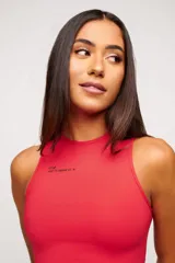 Top deportivo blanco de corte cropped, con cuello alto y logo estampado en el frente.