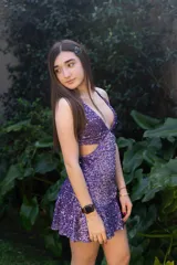 Vestido corto de lentejuelas color verde oliva, con escote en V, breteles finos cruzados en la espalda, cut-outs laterales y volado en el ruedo.