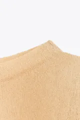 Top color beige de punto fino, con cuello barco y manga larga.
