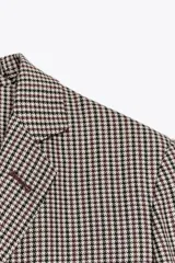 Blazer de cuello solapa y manga larga con estampado de cuadros en tonos marrón y blanco. Tiene bolsillos con solapa en el delantero, abertura en la espalda y cierre frontal con botones.