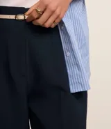 Pantalón de vestir azul marino, de corte zanahoria, con cinturón fino negro con hebilla dorada.