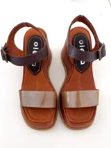 Sandalias de cuero color marrón con plataforma y tira delantera dorada. Tira trasera marrón con hebilla metálica.