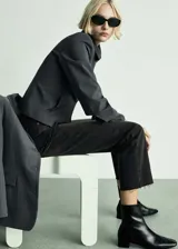 Pantalón de jean negro con lavado gastado, corte recto, tiro medio y terminación desflecada.