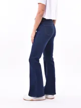 Jean de mezclilla azul de tiro alto, corte ajustado en muslos y pierna acampanada (estilo Oxford o flare).