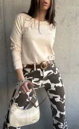 Remera beige de manga larga con cuello redondo y bordado floral en el escote.
