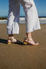 Sandalias de cuero doradas con tiras finas, suela plana y hebilla lateral.