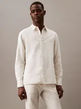 Camisa de manga larga color blanco hueso, confeccionada en lino y algodón. Tiene cuello clásico, cierre con botones y un bolsillo en el pecho.